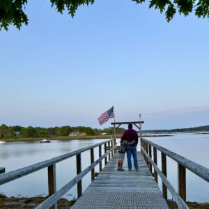 Two people standing on boat dock with flag
